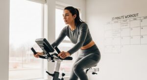 Mulher em treino de bike indoor com calendário de treinos ao fundo